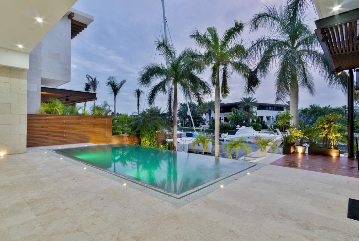 Vista de la terraza con alberca de una casa de lujo en venta en Puerto Cancún, con diseño moderno, increible iluminación y diseños de lujo.
